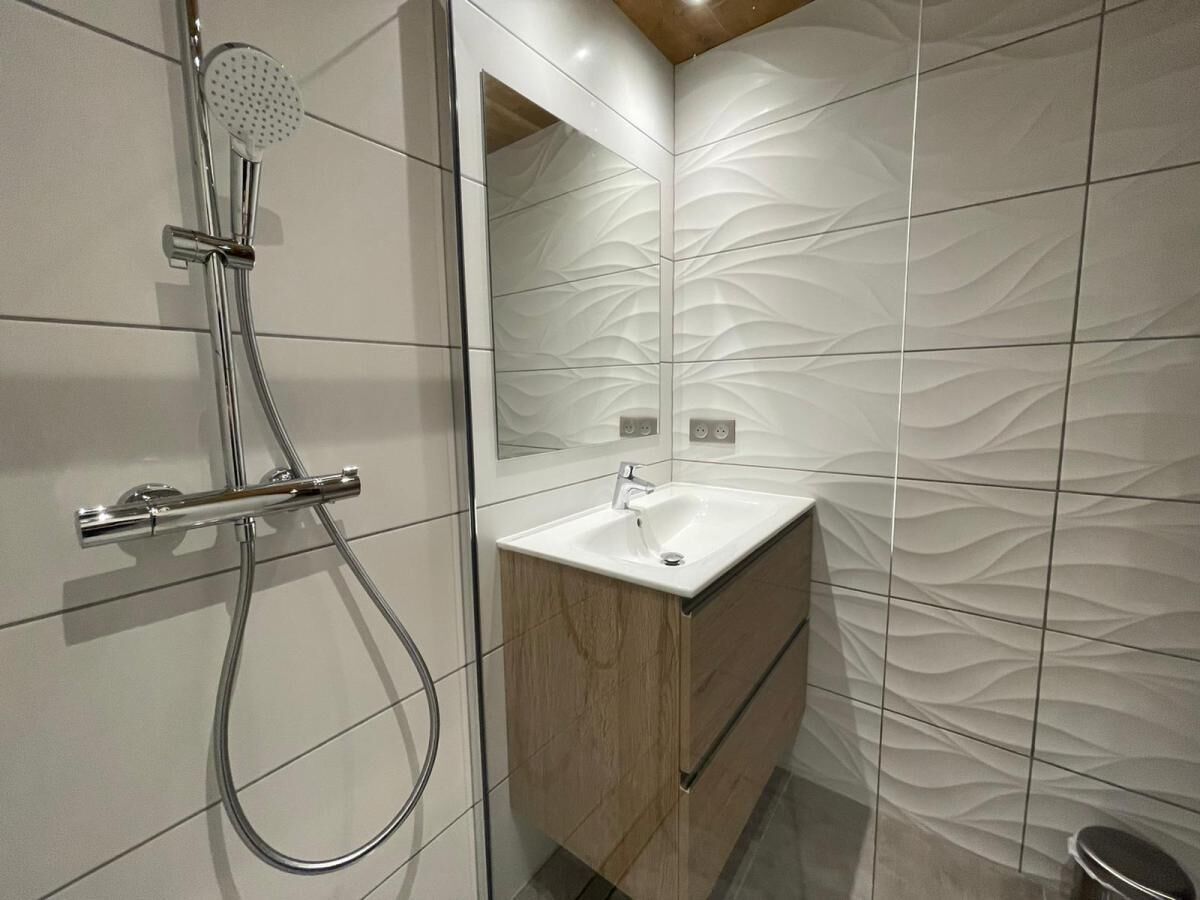Un bagno moderno con doccia, lavandino e mobile bagno in legno.