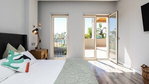 Quarto com cama, mesa de cabeceira, abajur e porta de vidro corrediça para uma varanda.
