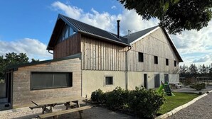 A modern building with a sloped roof, large windows, and a wooden exterior.
