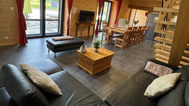A modern interior with a sofa, a wooden coffee table, and a dining area with wooden chairs and a table.