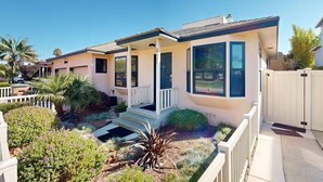 Une maison de plain-pied dotée d’un porche abrité, d’un garage et d’un jardin bien entretenu, agrémenté de diverses plantes et arbustes.