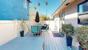 Une terrasse avec une table et des chaises, un parasol noir et des plantes en pot.