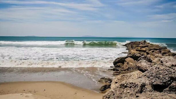 Une côte rocheuse où les vagues se brisent sur la plage.