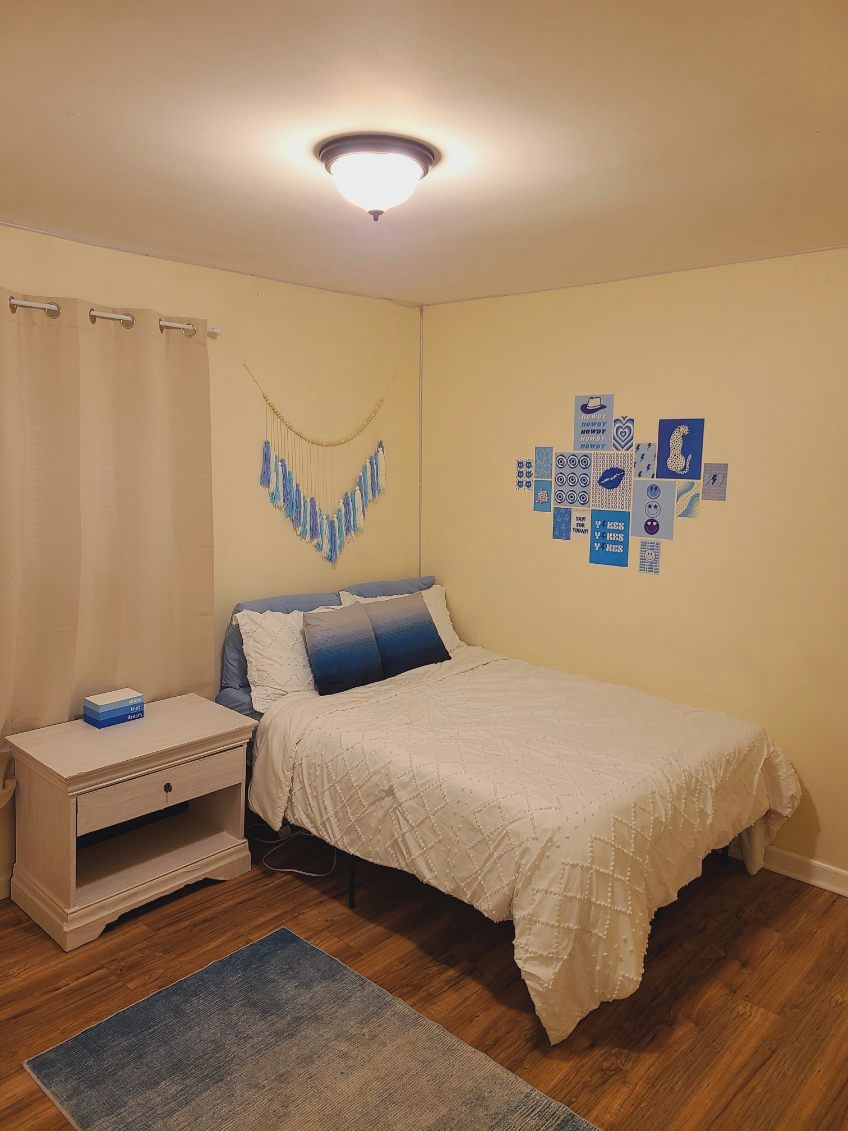 Un dormitorio con cama, mesita de noche y adornos en la pared.