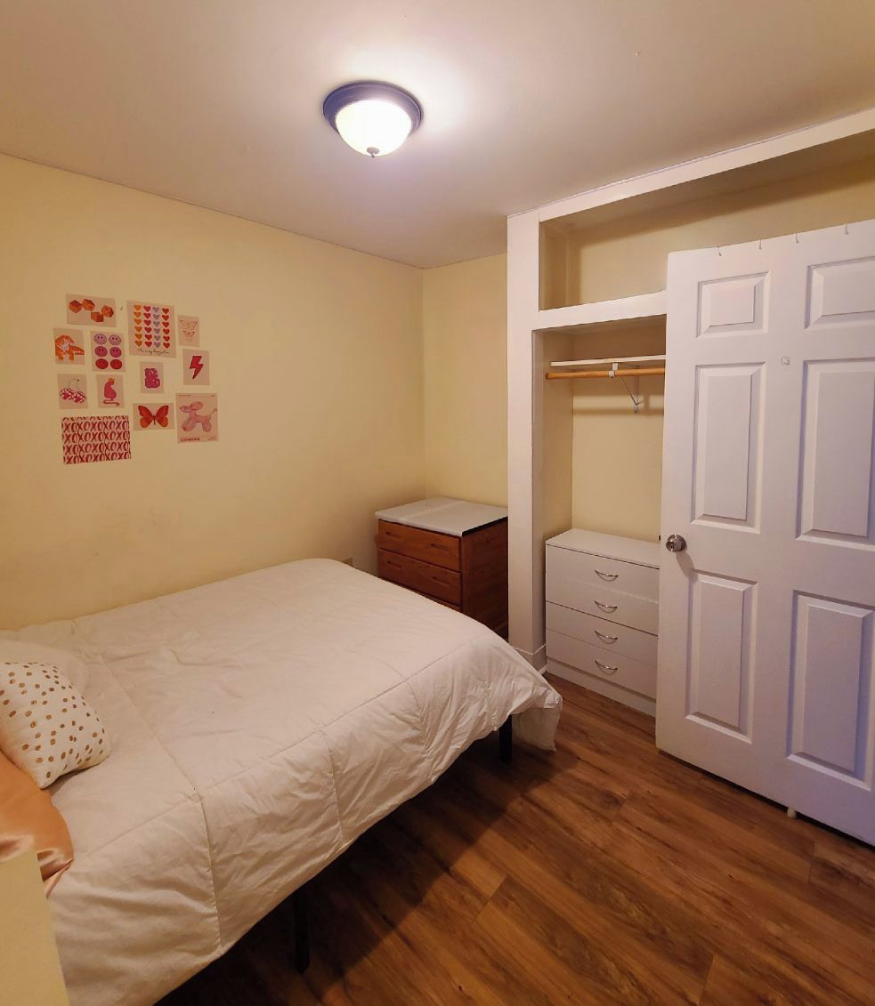 Une chambre à coucher comprenant un lit, une table de chevet, une commode et un placard.