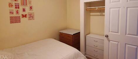 Une chambre à coucher comprenant un lit, une table de chevet, une commode et un placard.