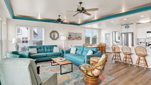 Un salon spacieux avec des canapés de couleur turquoise, une table basse et des fauteuils en osier.