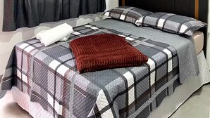 A bedroom with a bed, black curtains, an air conditioning unit, and a headboard. - Pousada Suite Suzena (Penha)