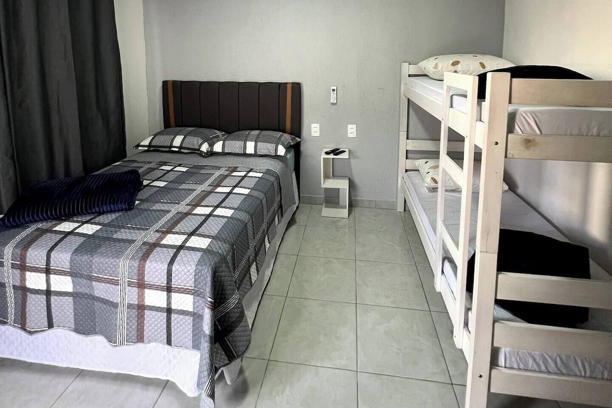 A room with a bed, a nightstand, and a bunk bed.