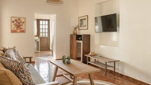 Una sala de estar con un sofá, una mesa de madera, un televisor y un aparador.
