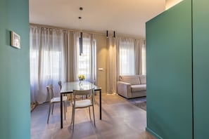 A modern living room with a glass dining table, beige sofa, and curtains. - Sanremo Belle Epoque Apartment by Wonderful Italy (Sanremo)