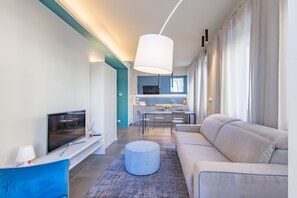 A modern living room with a TV, sofa, ottoman, and a dining area in the background. - Sanremo Belle Epoque Apartment by Wonderful Italy (Sanremo)
