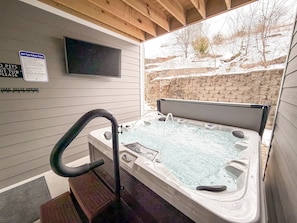 A hot tub with a built-in TV, a safety sign, and a wooden deck. - Summer Special Hot Tub No Dog Fee Near SD City & Strip No Steps (Branson)