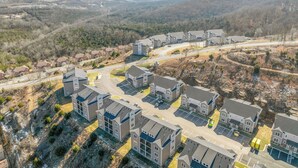 A residential area with modern houses, a central road, and a hilly landscape in the background.
