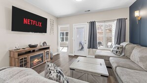 A living room with a fireplace, a flat-screen TV mounted on the wall, a sofa, and a coffee table.