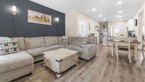 A modern living room with a sectional sofa, a wooden coffee table, and a dining area with a table and chairs.