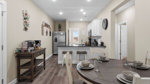 A modern kitchen with a central island, white cabinets, and a dining area with a round table set for four.