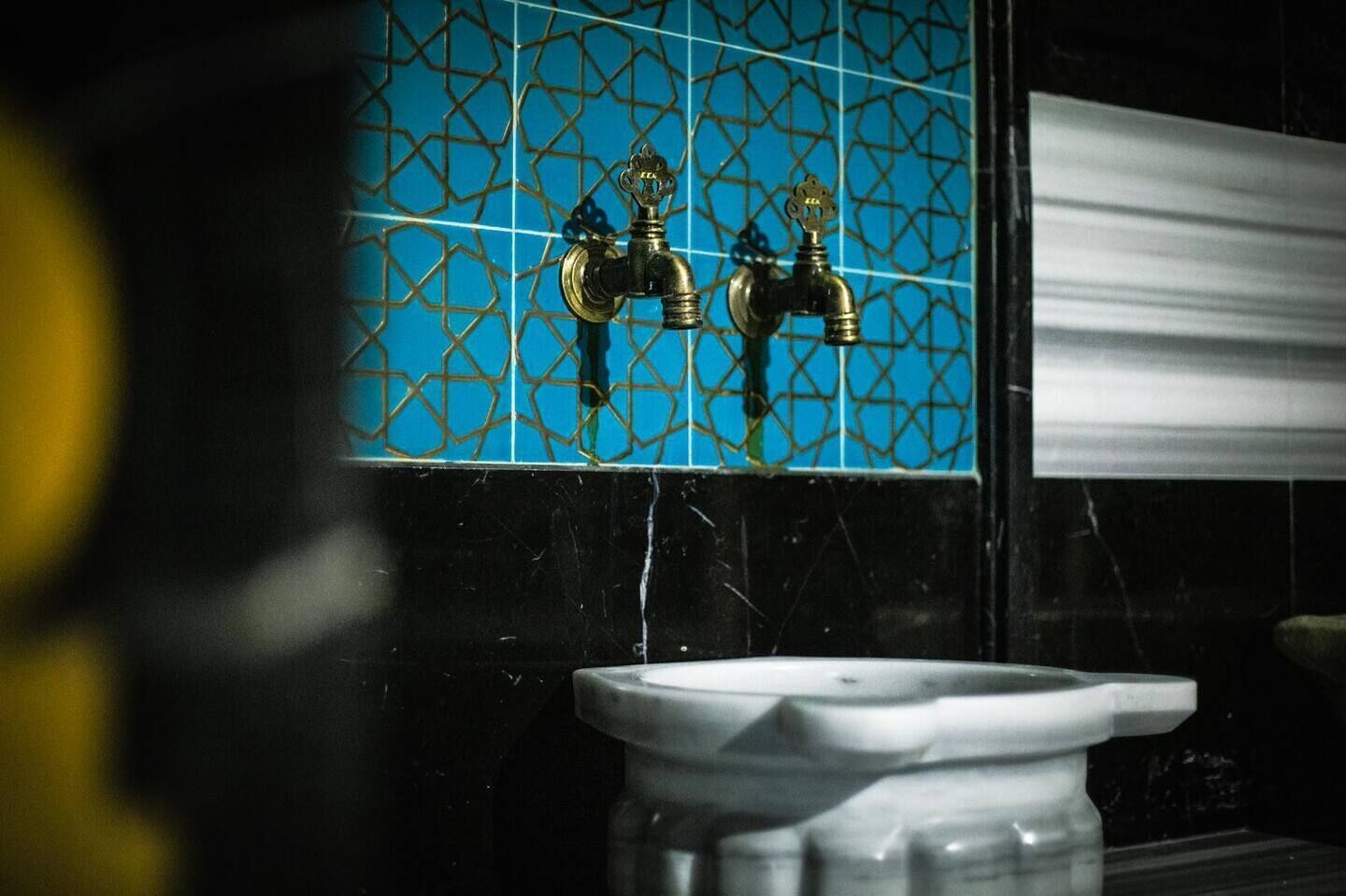Een badkamer met een wastafel en twee kraanwerk.