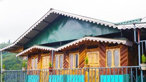 A wooden house with a green roof and a balcony with a metal railing. - Home in the lap of nature 
In a peaceful location..... Darjeeling (WB)