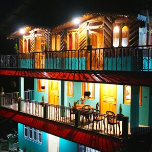 A two-story building with balconies, wooden railings, and potted plants.