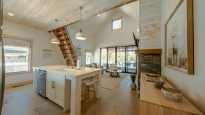 Una cocina amplia con una isla grande, techo de madera y chimenea de piedra.
