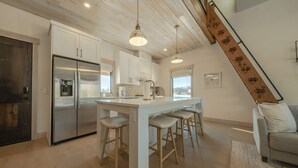 Una cocina moderna con una isla central, electrodomésticos de acero inoxidable y taburetes de madera.