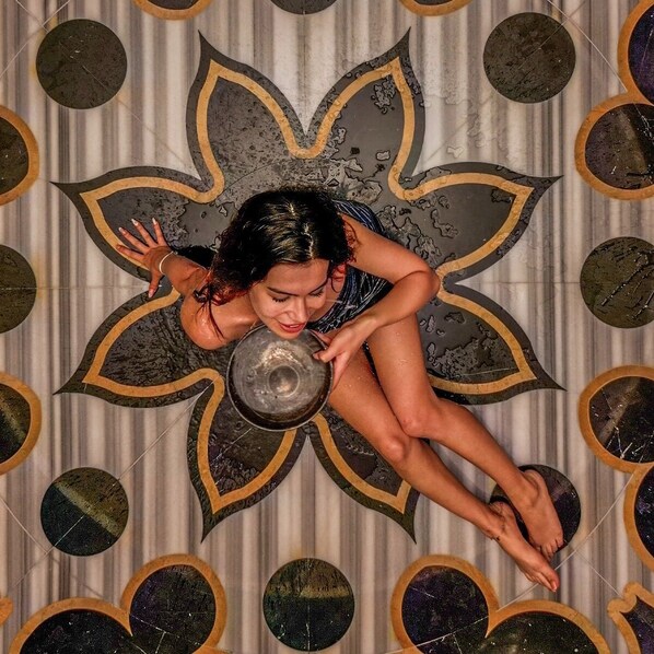 A person lying on a floor with a circular pattern and a central design resembling a flower.