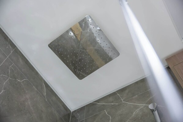 A corner of a room with a white wall, a metallic vent, and a tiled floor.