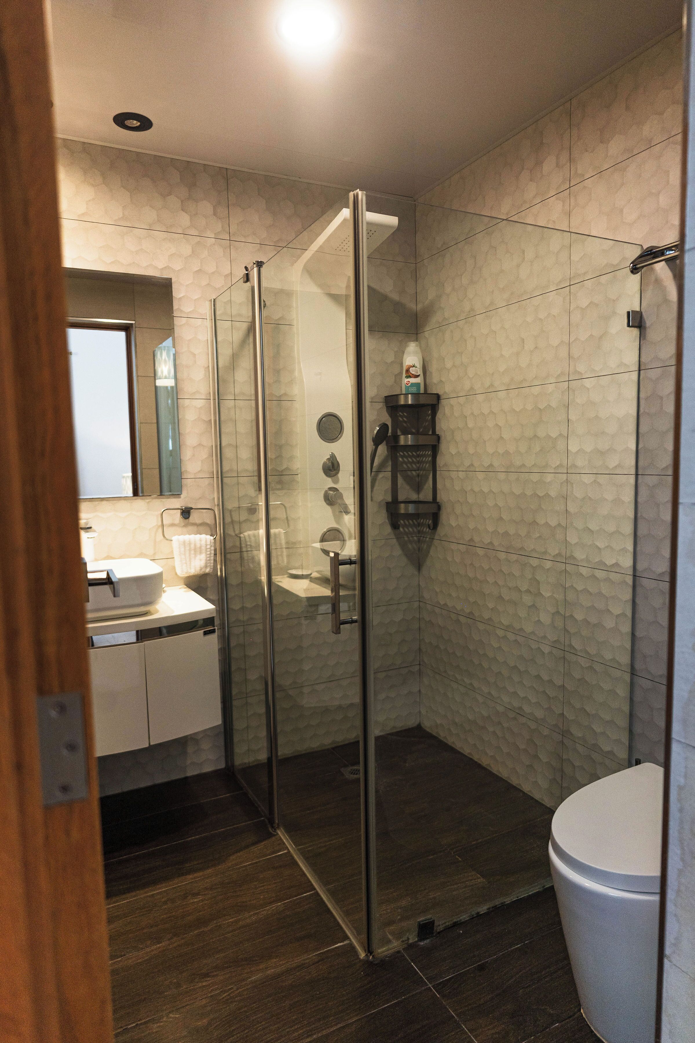 A modern bathroom with a glass-enclosed shower, a white sink, and a toilet.