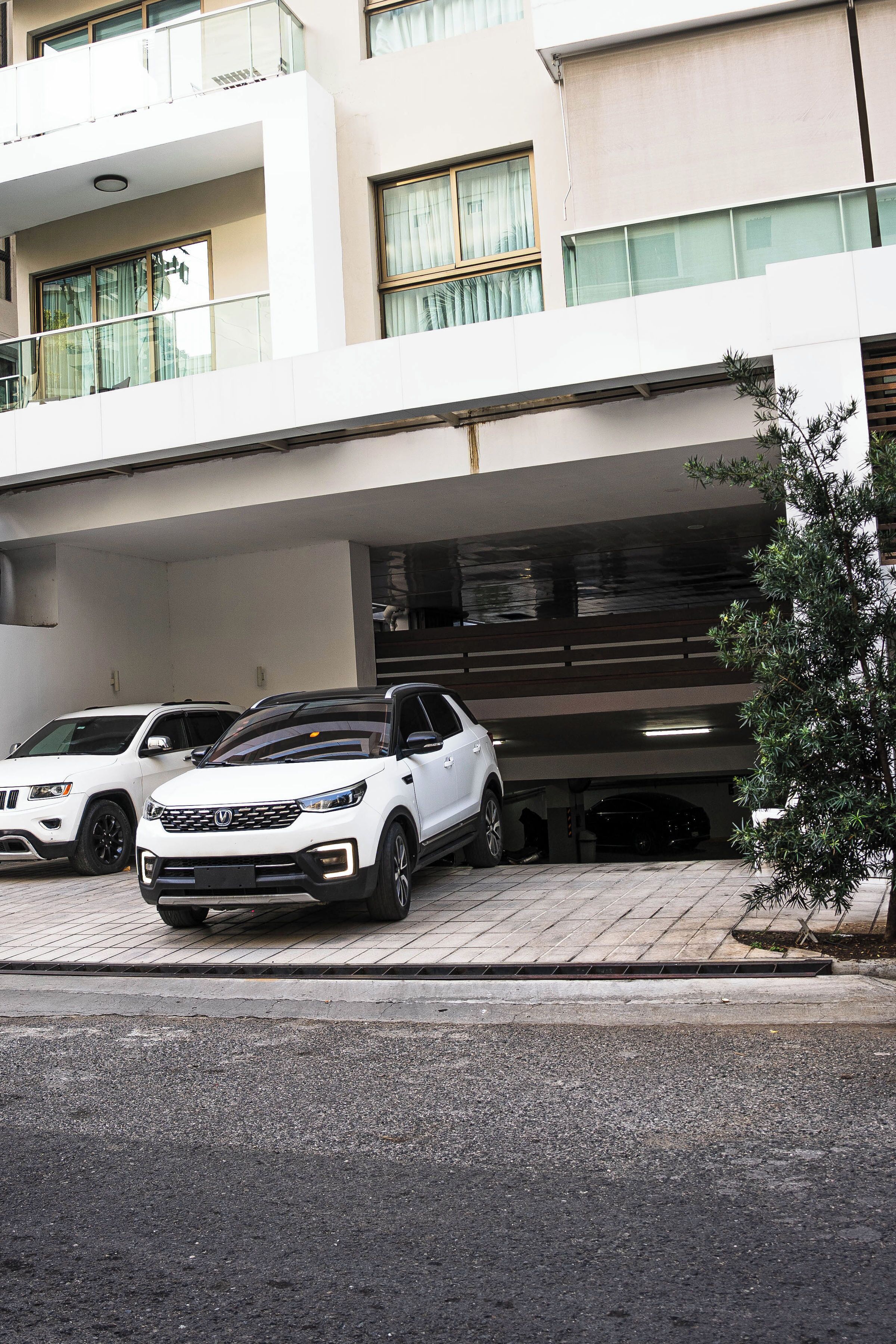 A modern building with a covered parking area and a white car parked in front.