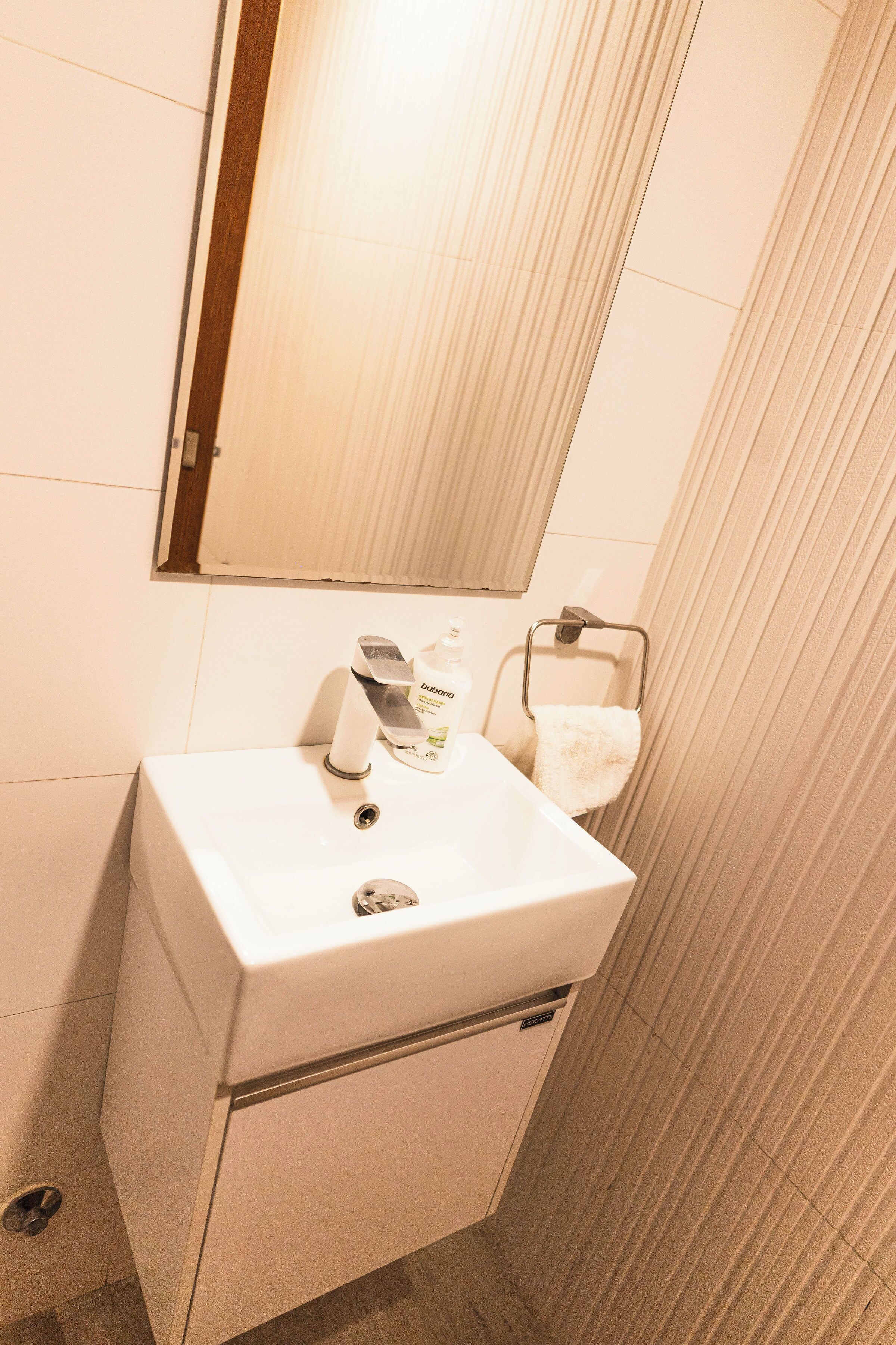 Une salle de bain avec un lavabo blanc, un miroir et un porte-serviettes.