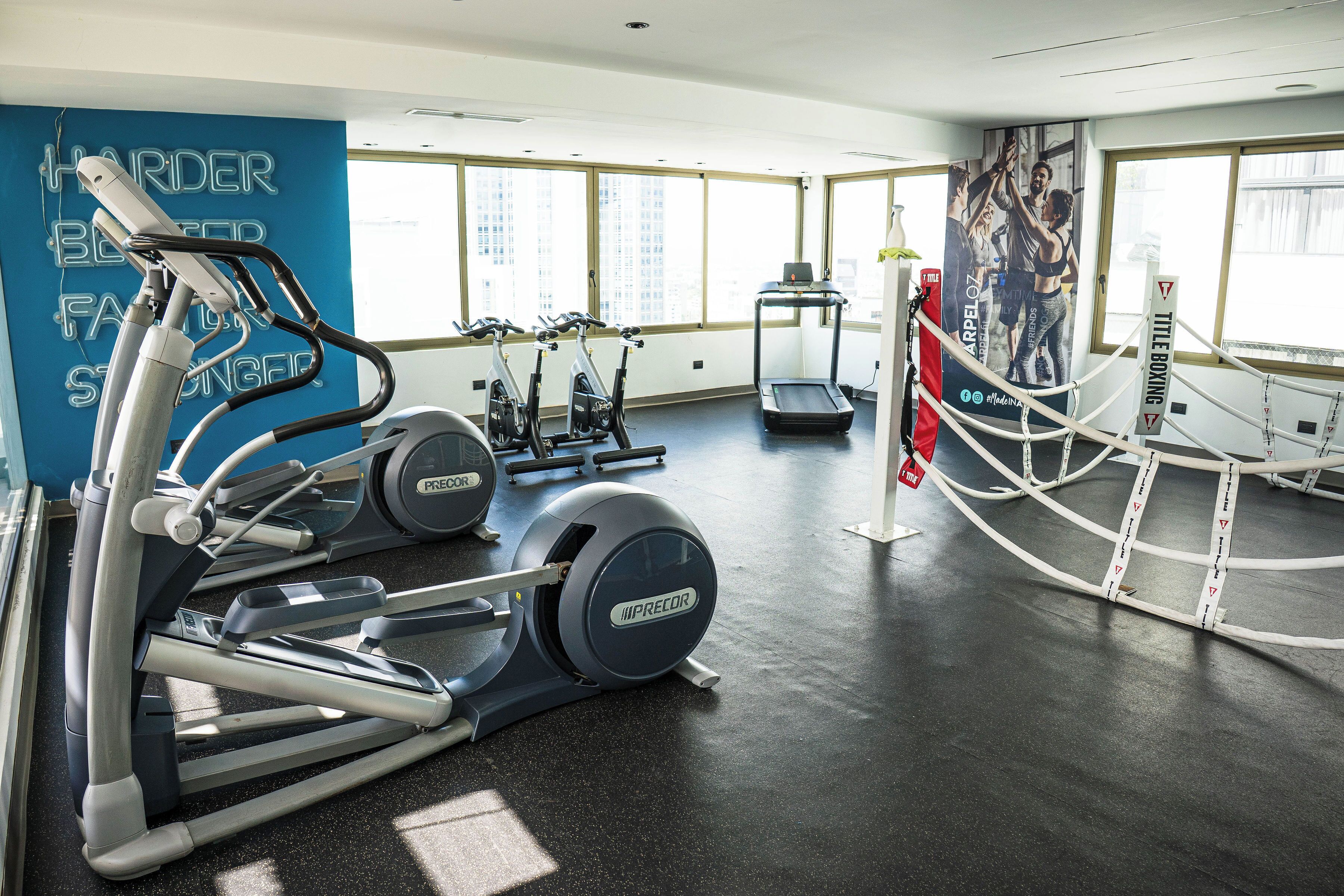 Un gimnasio con cintas de correr, elípticas y un ring de boxeo.