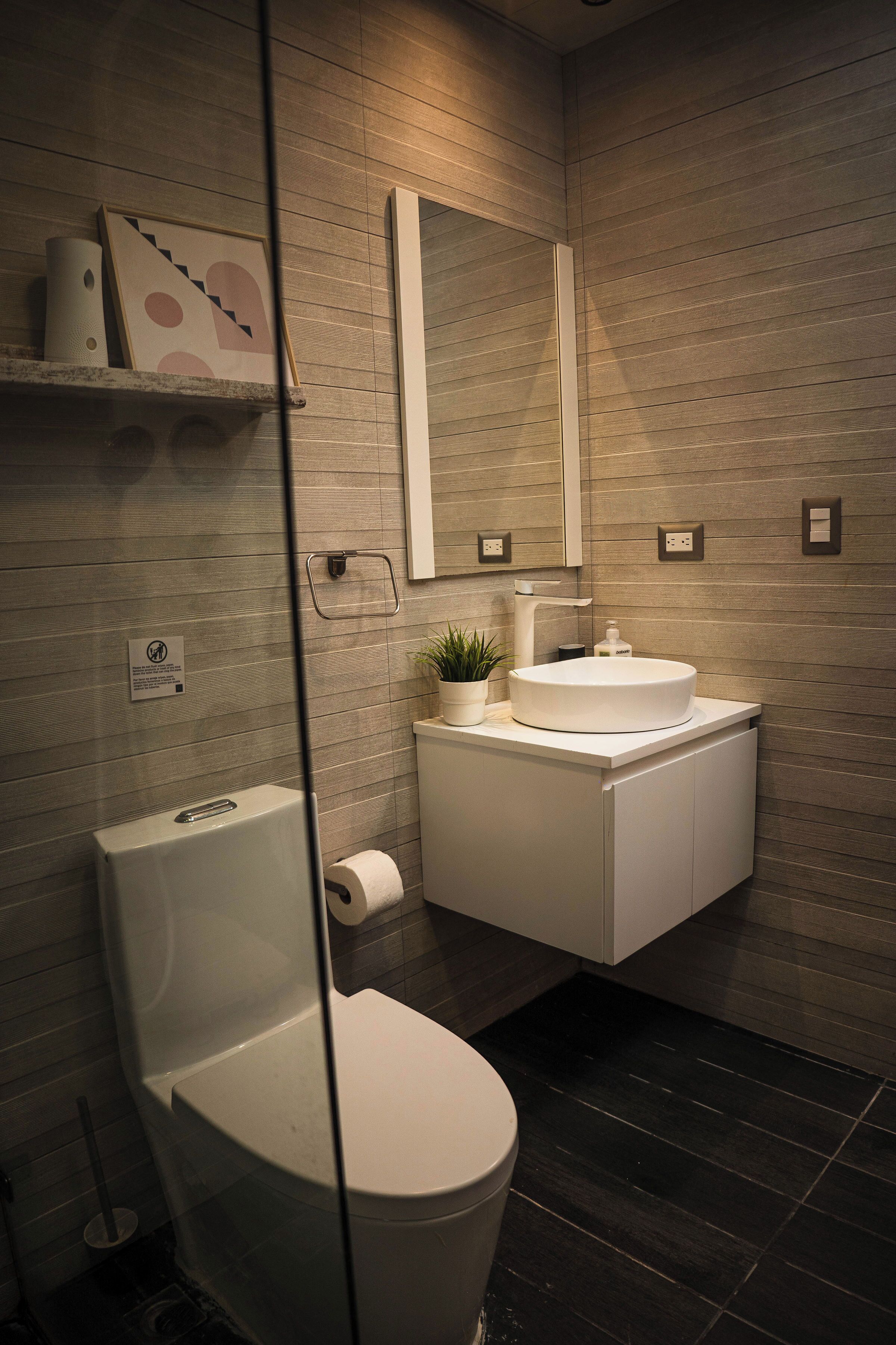 A modern bathroom with a toilet, sink, and mirror.