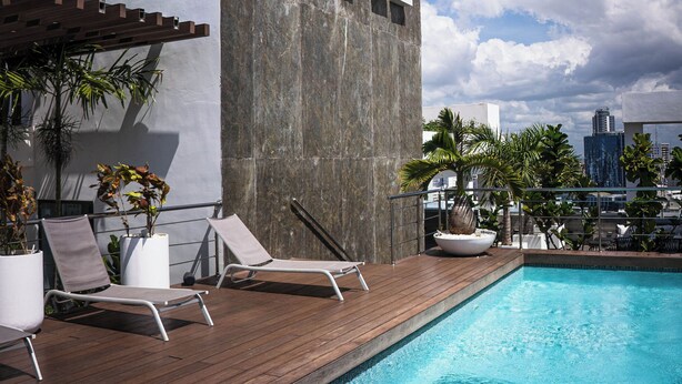 A modern building with the name 'ARPEL' on its facade, a swimming pool, and lounge chairs. - Arpel 07 - Piantini - Santo Domingo (Santo Domingo)