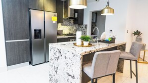 A modern kitchen with a marble island, stainless steel appliances, and contemporary lighting. - Arpel 07 - Piantini - Santo Domingo (Santo Domingo)