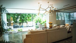 A modern living room with a large beige sectional sofa, a decorative vase with flowers, and a unique geometric light fixture. - Arpel 07 - Piantini - Santo Domingo (Santo Domingo)