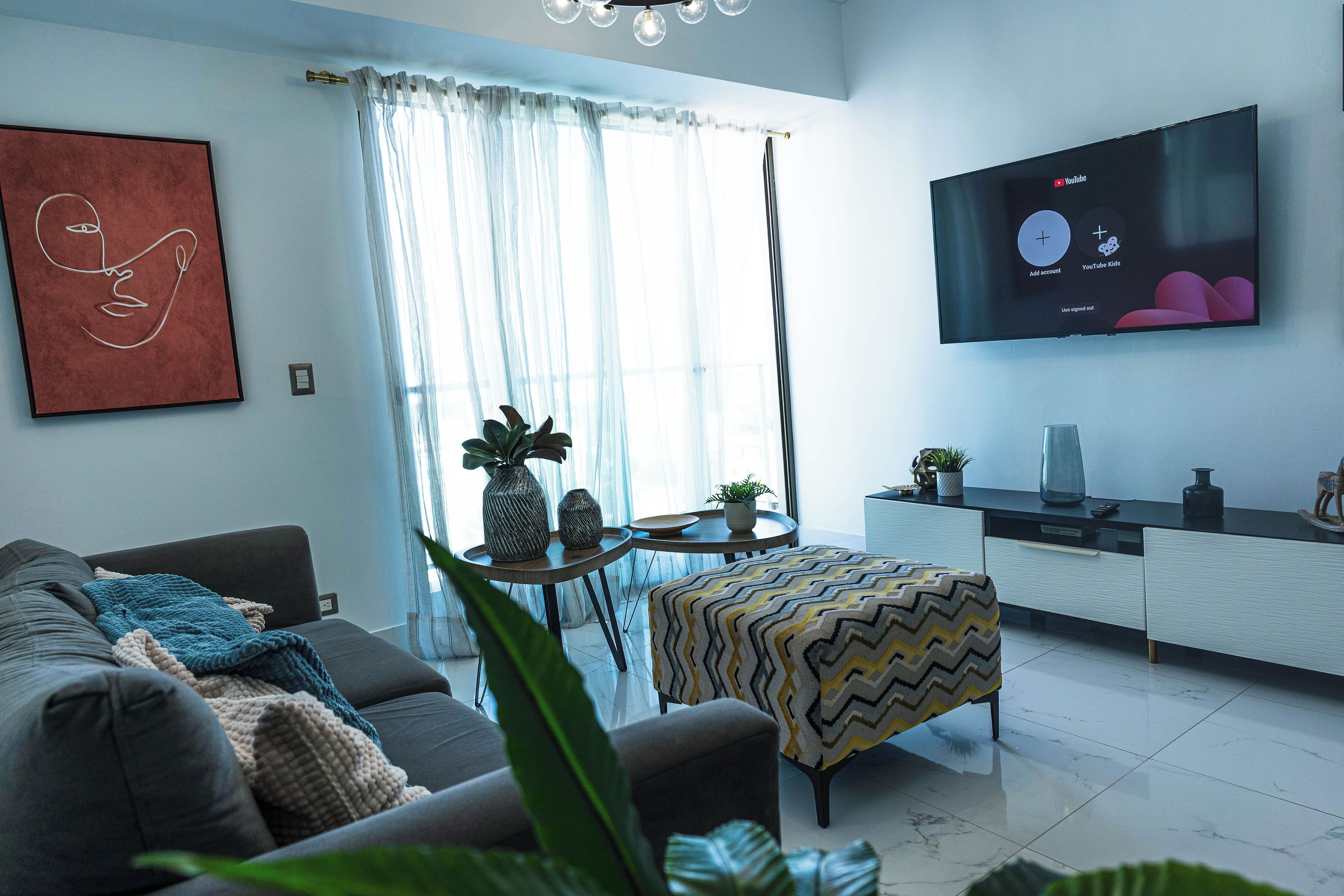 A modern living room with a sofa, a coffee table, and a TV mounted on the wall.