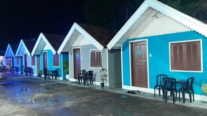 A row of small, brightly colored cottages with doors and windows, each with a small table and chairs outside. - Pousada Do Sol (Rio de Janeiro)