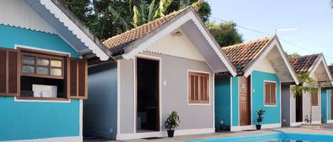 A residential area with a swimming pool, houses with tiled roofs, and potted plants.