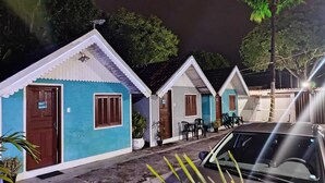 A row of small, single-story buildings with a uniform architectural style, each featuring a door and window, and a small outdoor seating area. - Pousada Do Sol (Rio de Janeiro)
