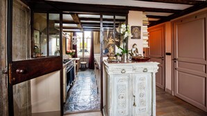 Un pasillo con un armario blanco, vigas de madera y una puerta que da a una cocina.