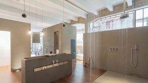 Un baño moderno con un lavamanos grande, espejo y zona de ducha.
