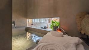 Un cuarto de spa con una bañera, una toalla, una planta y una ventana con vistas al exterior.