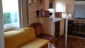 Un espacio habitable compacto con sofá, kitchenette y un pequeño comedor.