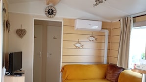Un espacio habitable pequeño con un sofá, una mesita, un televisor y un reloj en la pared.