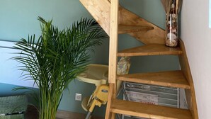 Eine Holztreppe mit einer Ziegelwand darüber und einer grünen Wand zur Rechten, sowie eine Pflanze mit Pampasgras.