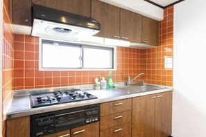 Une cuisine équipée d’une cuisinière à gaz, d’un lave-vaisselle, de meubles en bois et d’une fenêtre au-dessus de l’évier.