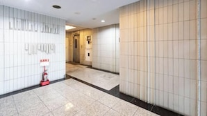 En hotellobby med ett klinkergolv, en brandsläckare och en receptionsdisk.
