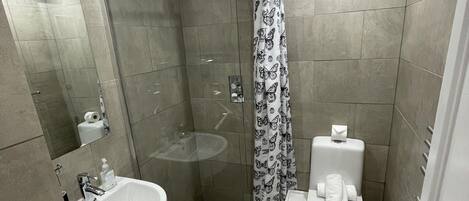 A modern bathroom with a shower, sink, toilet, and a mirror.
