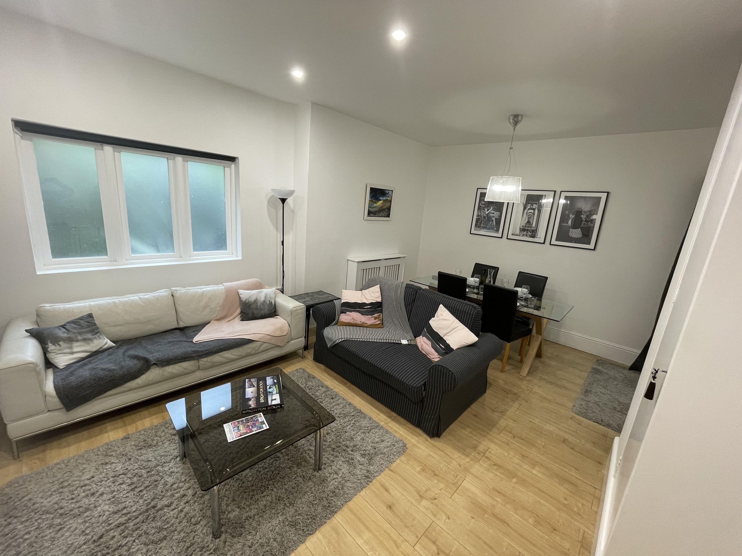 A modern living room with a sofa, a coffee table, and a dining area with chairs and a table.